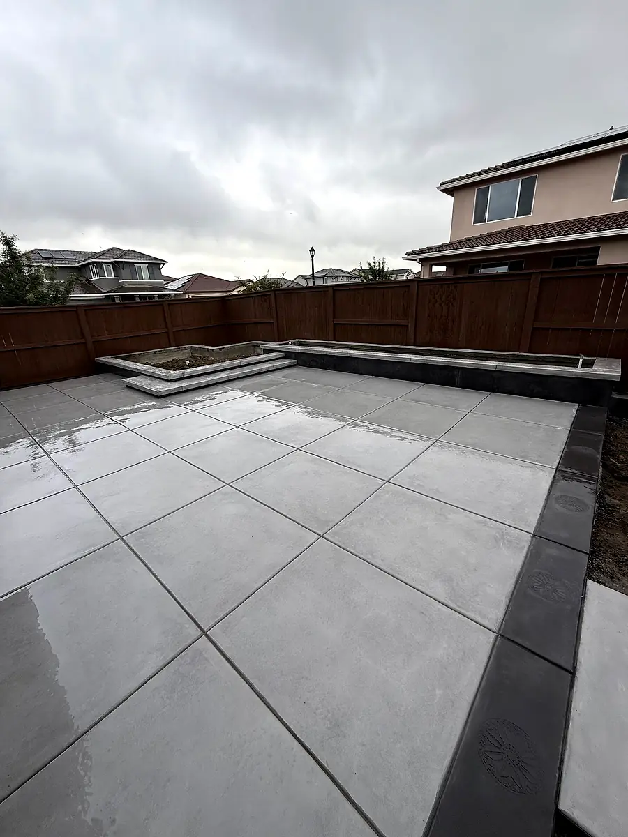 Backyard concrete slab with a dark border and raised concrete planter