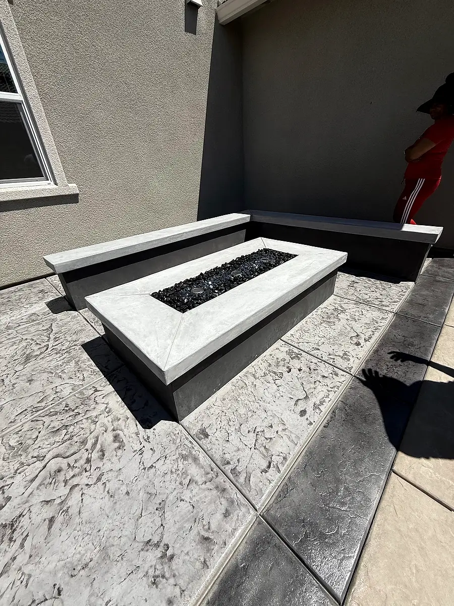 Concrete fire pit and built-in bench on a gray stamped concrete patio