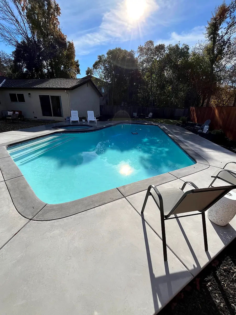 Concrete pool deck around a freeform pool in a backyard