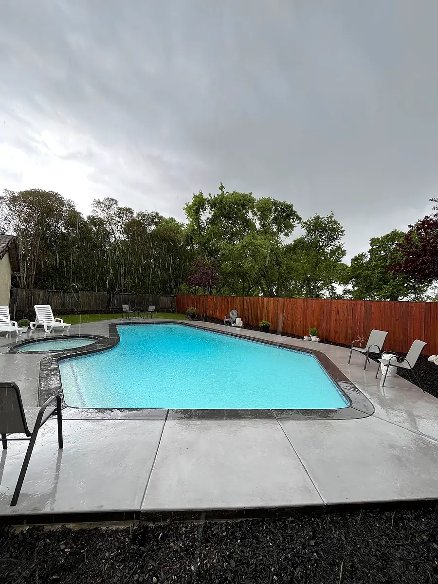 Concrete pool deck with a smooth coping band around a freeform pool and spa