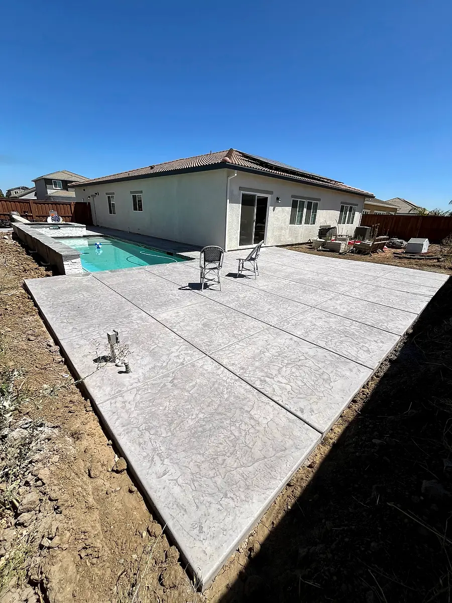 New concrete pool deck and patio beside a pool and spa