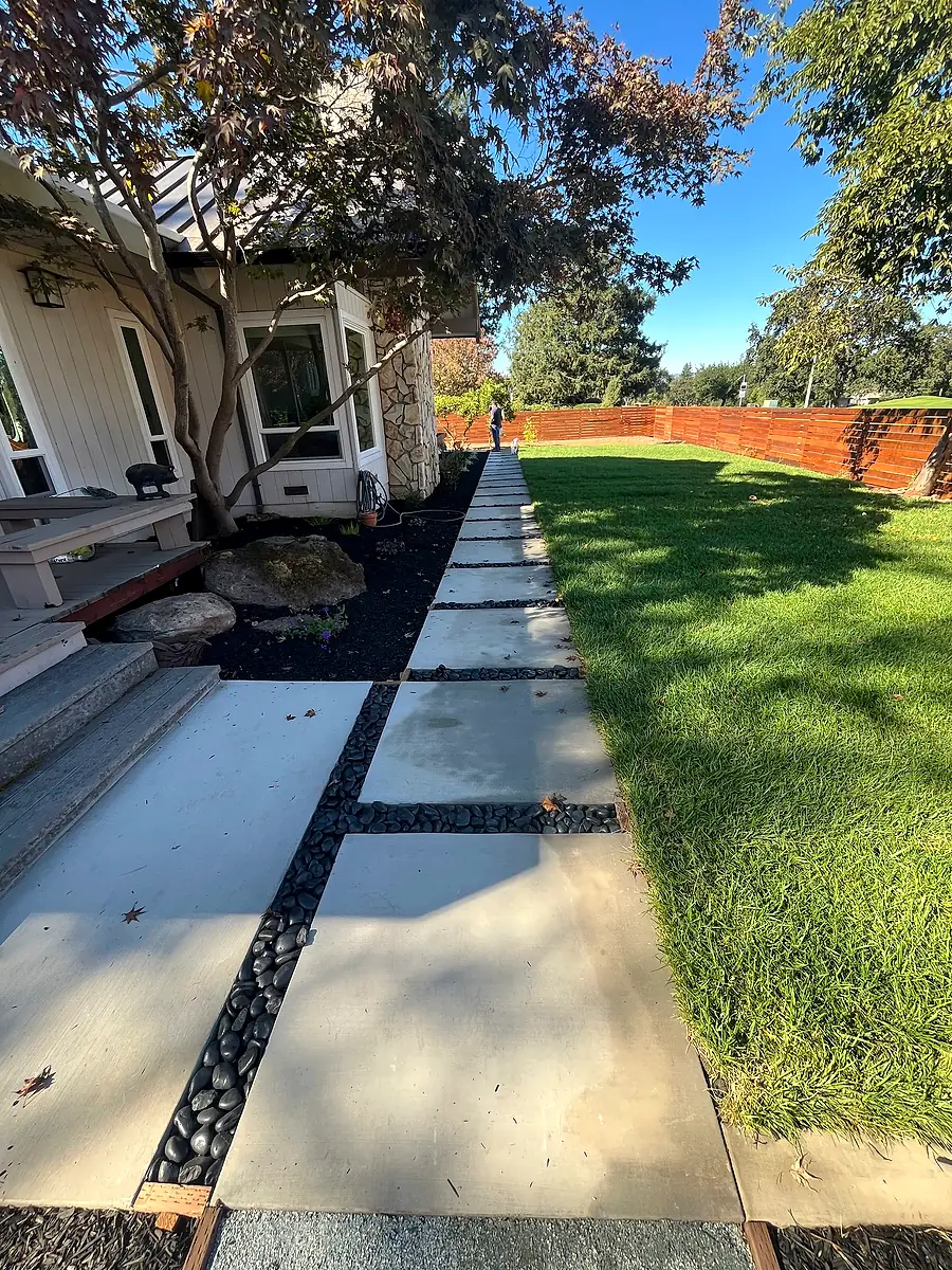 Concrete walkway with river rock joints beside a lawn