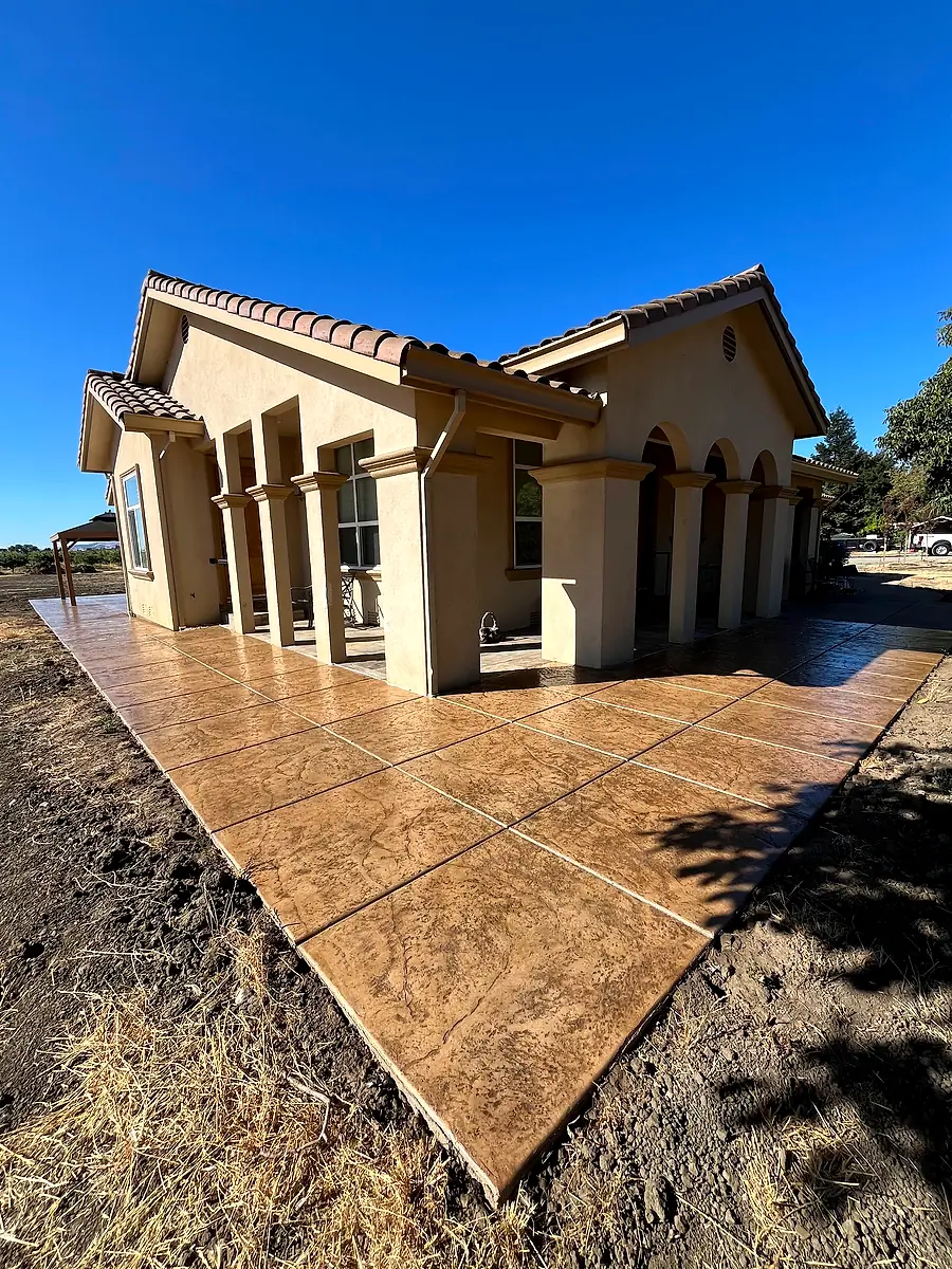 Stamped concrete wraparound patio along a home with white columns