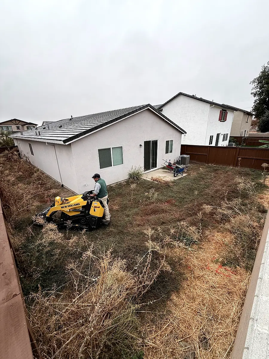 Crew clearing a Woodland backyard with a compact track loader before concrete work