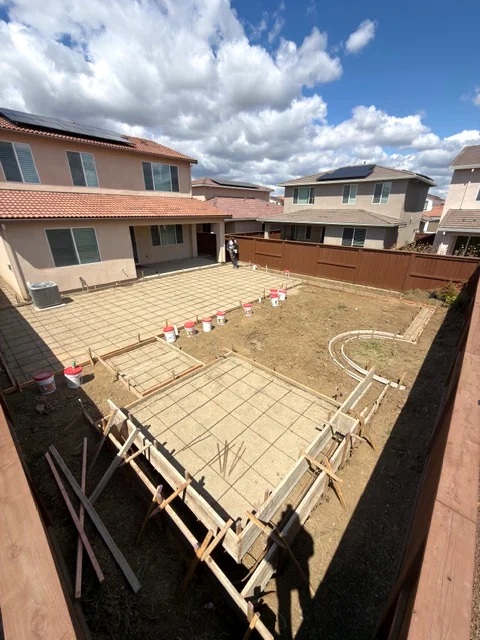 New-build backyard in Woodland's Spring Lake with patio forms, rebar and a curved mow strip laid out before the pour