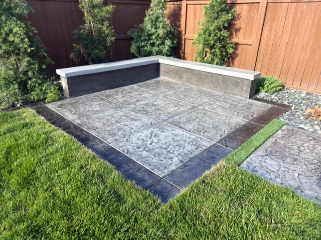 Custom L-shaped concrete bench on a stamped seating pad with a charcoal border in Woodland