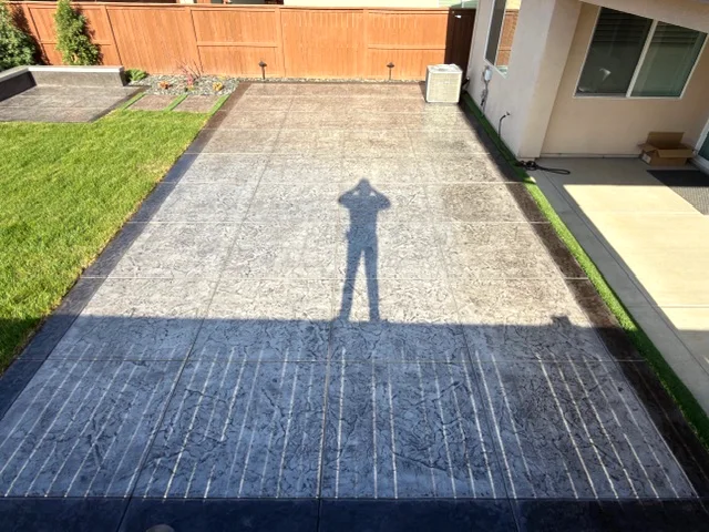 Long stamped and colored concrete patio with a charcoal border along a new home in Woodland