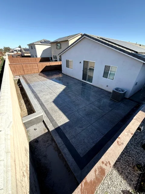 Full-yard stamped concrete patio with a charcoal border band in Woodland's Spring Lake