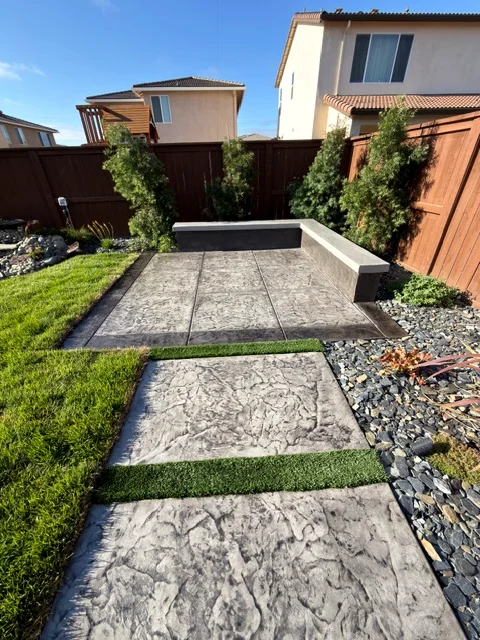 Stamped concrete stepping pads with turf joints leading to a seating area in Woodland