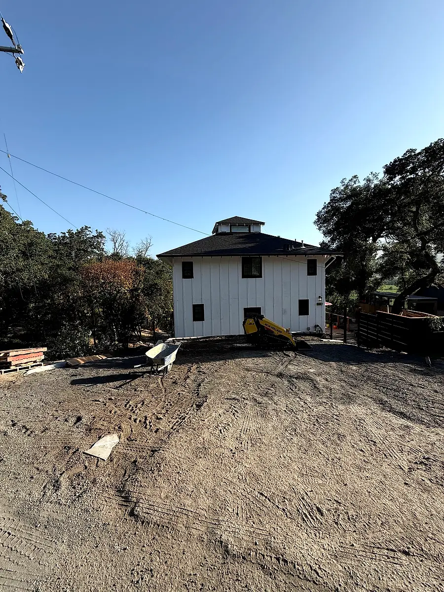 Yountville property graded and ready for new concrete, white farmhouse in background