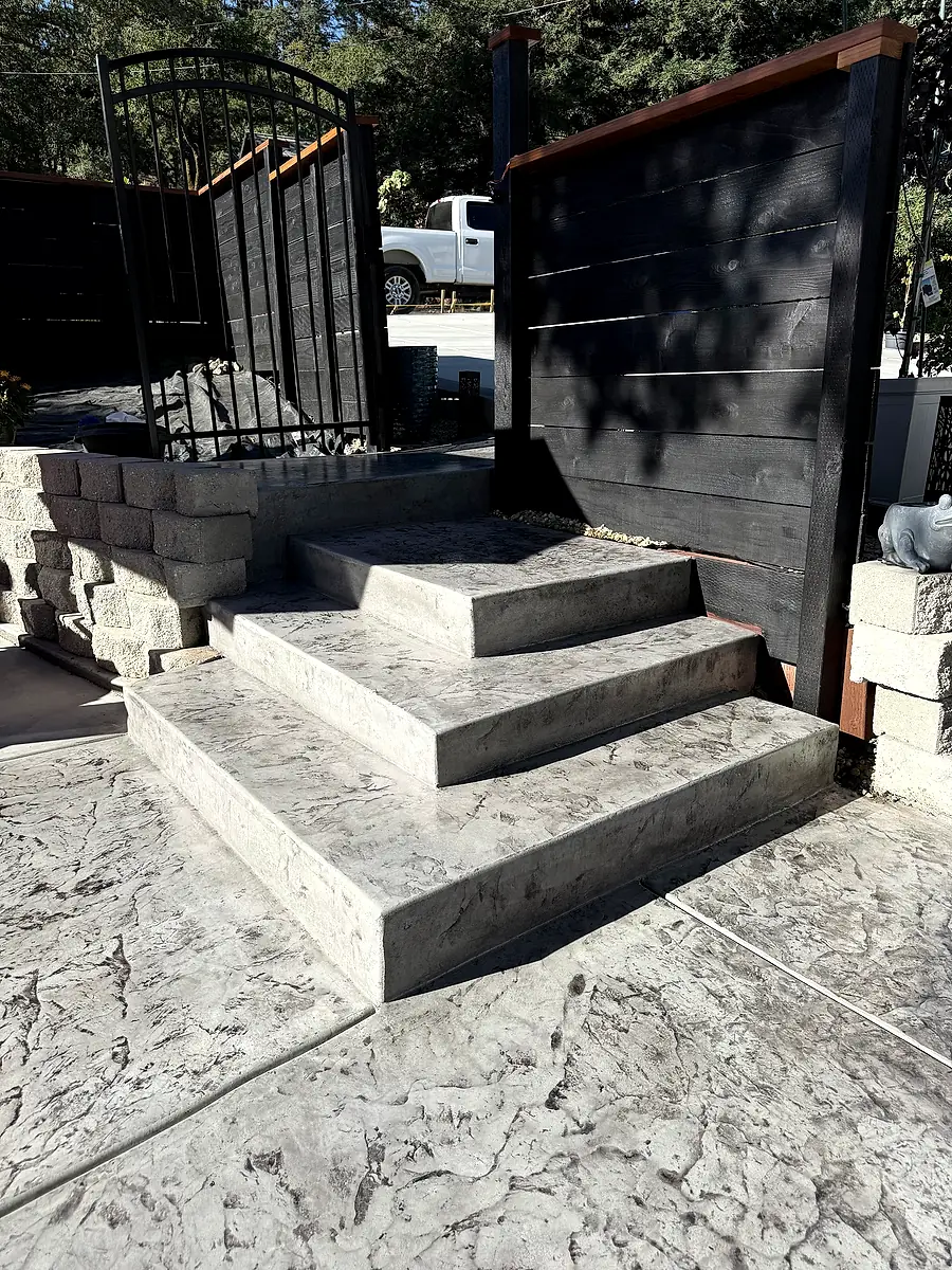 Finished stamped concrete steps and landing by a dark wood gate in Yountville